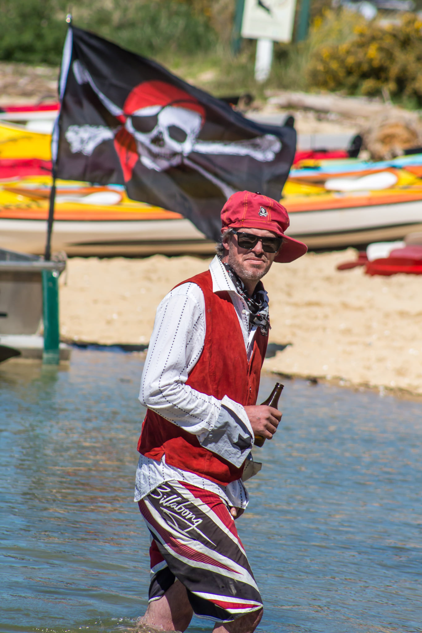 man on beach in pirate dress-up with pirate flag